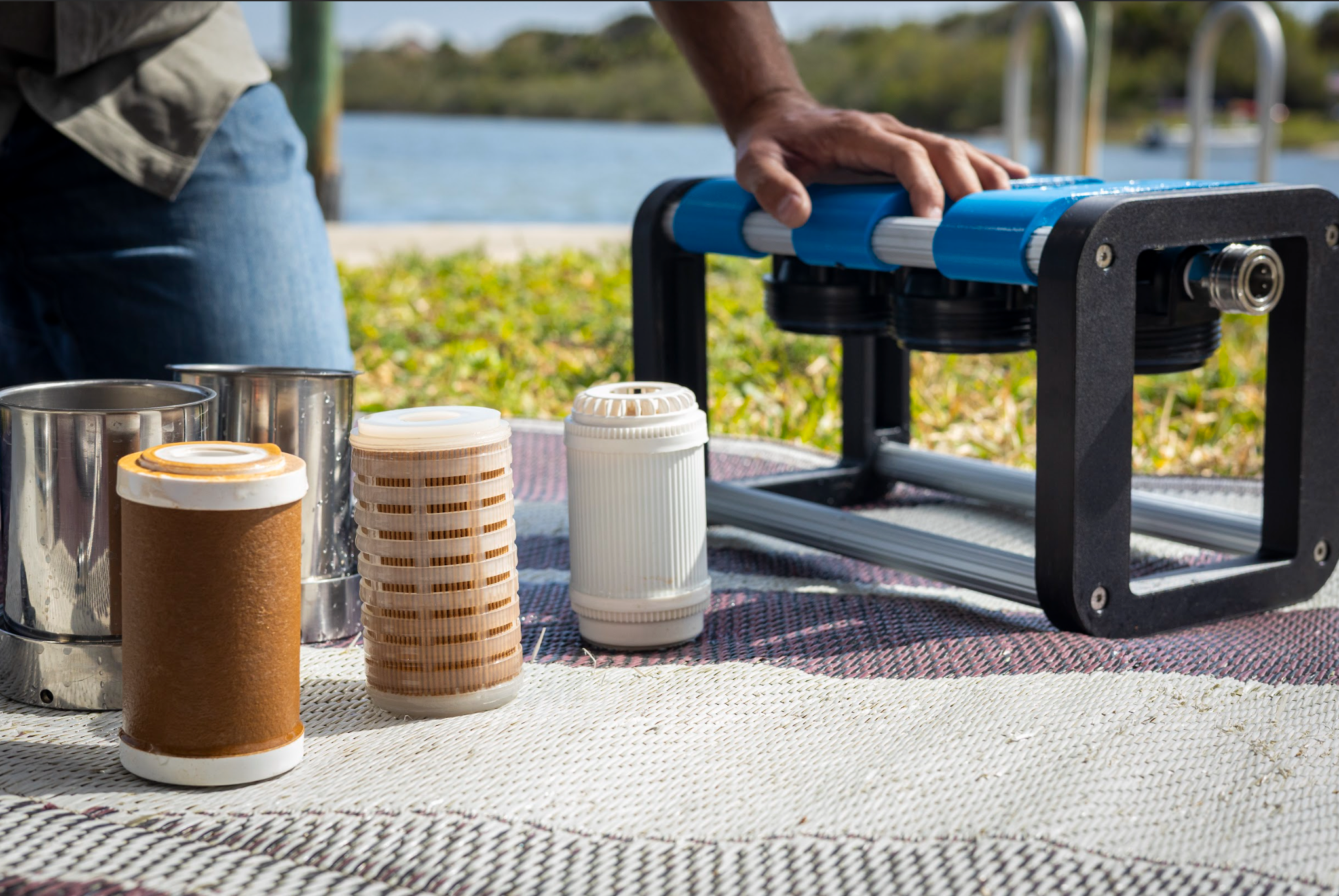 Person using a portable water filter by a lake